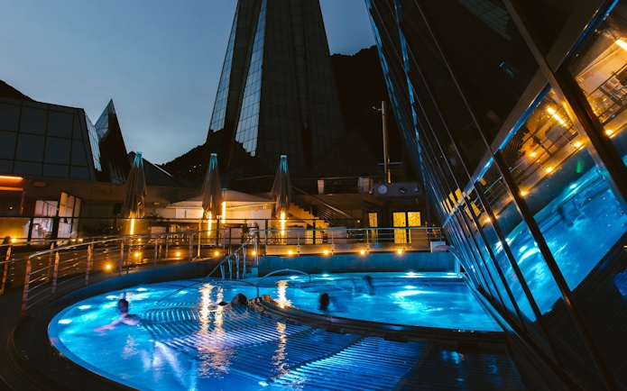 Outdoor lagoon at Caldea thermal spa illuminated at night with modern architecture.