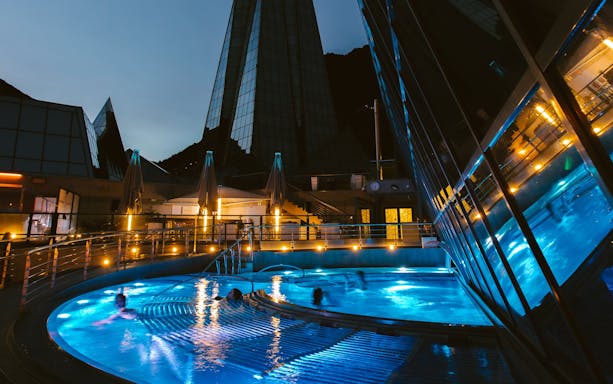 Outdoor lagoon at Caldea thermal spa illuminated at night with modern architecture.