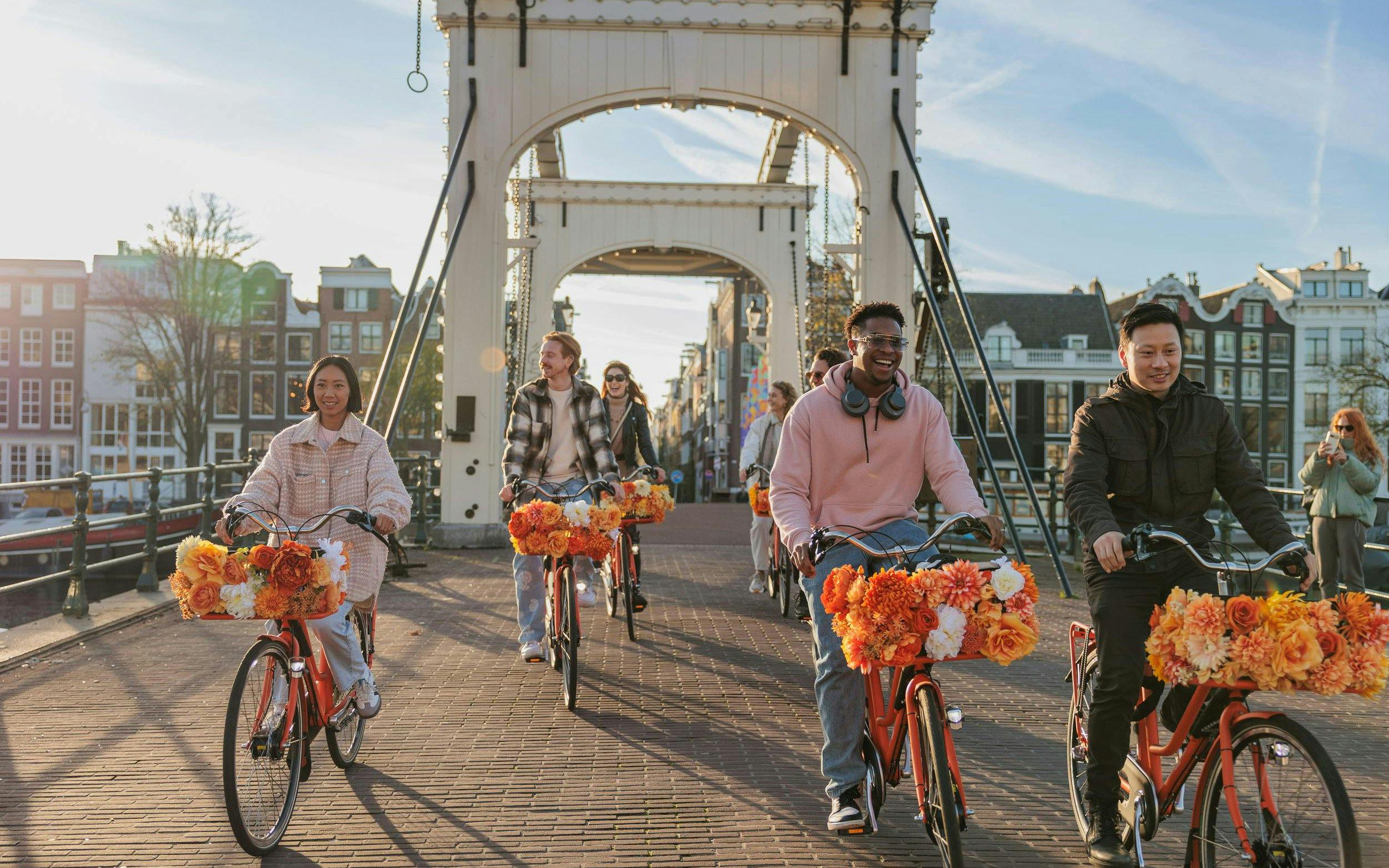Cyclists on a bridge during a city bike tour with flower-adorned bikes.