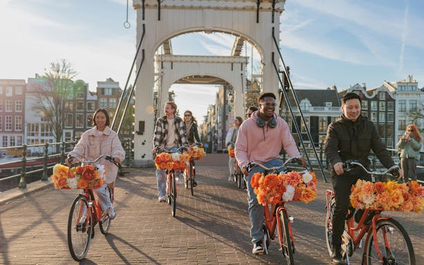 Cyclists on a bridge during a city bike tour with flower-adorned bikes.
