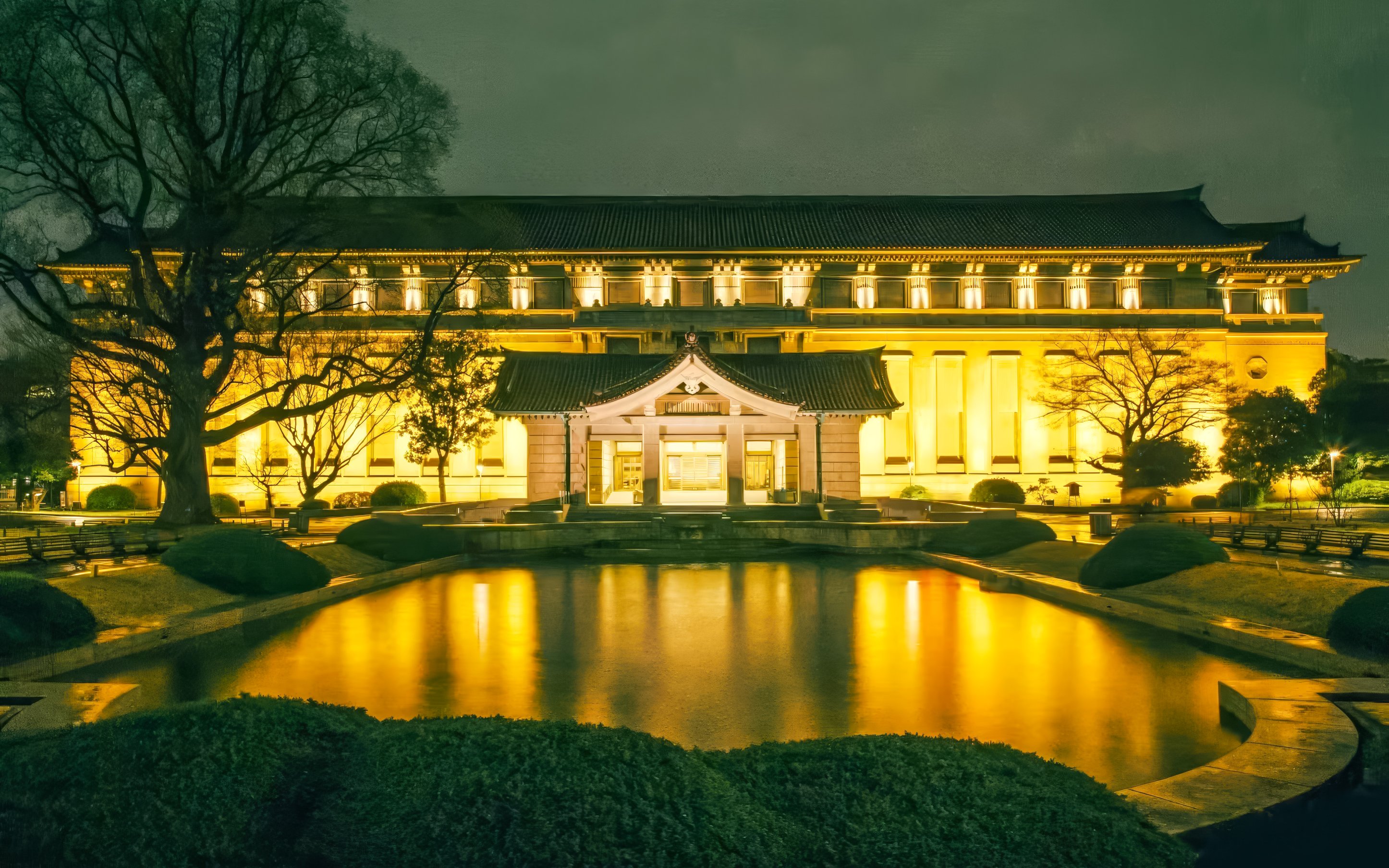 Honkan of Tokyo National Museum illuminated at night with reflection in pond.