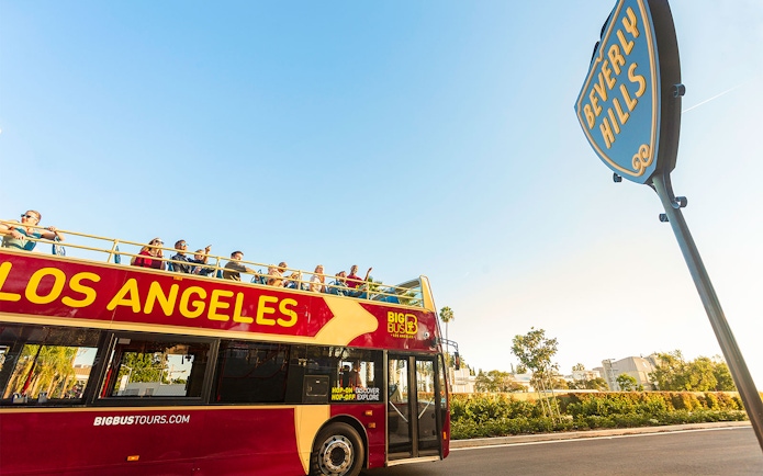Los Angeles hop-on hop-off tour bus near Beverly Hills sign.