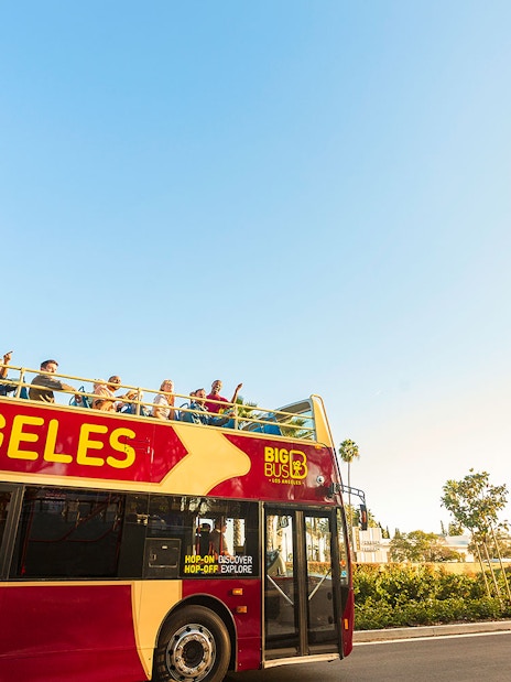 Los Angeles hop-on hop-off tour bus near Beverly Hills sign.