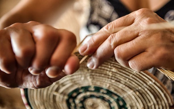 Hands weaving a basket during a workshop in Castelsardo.