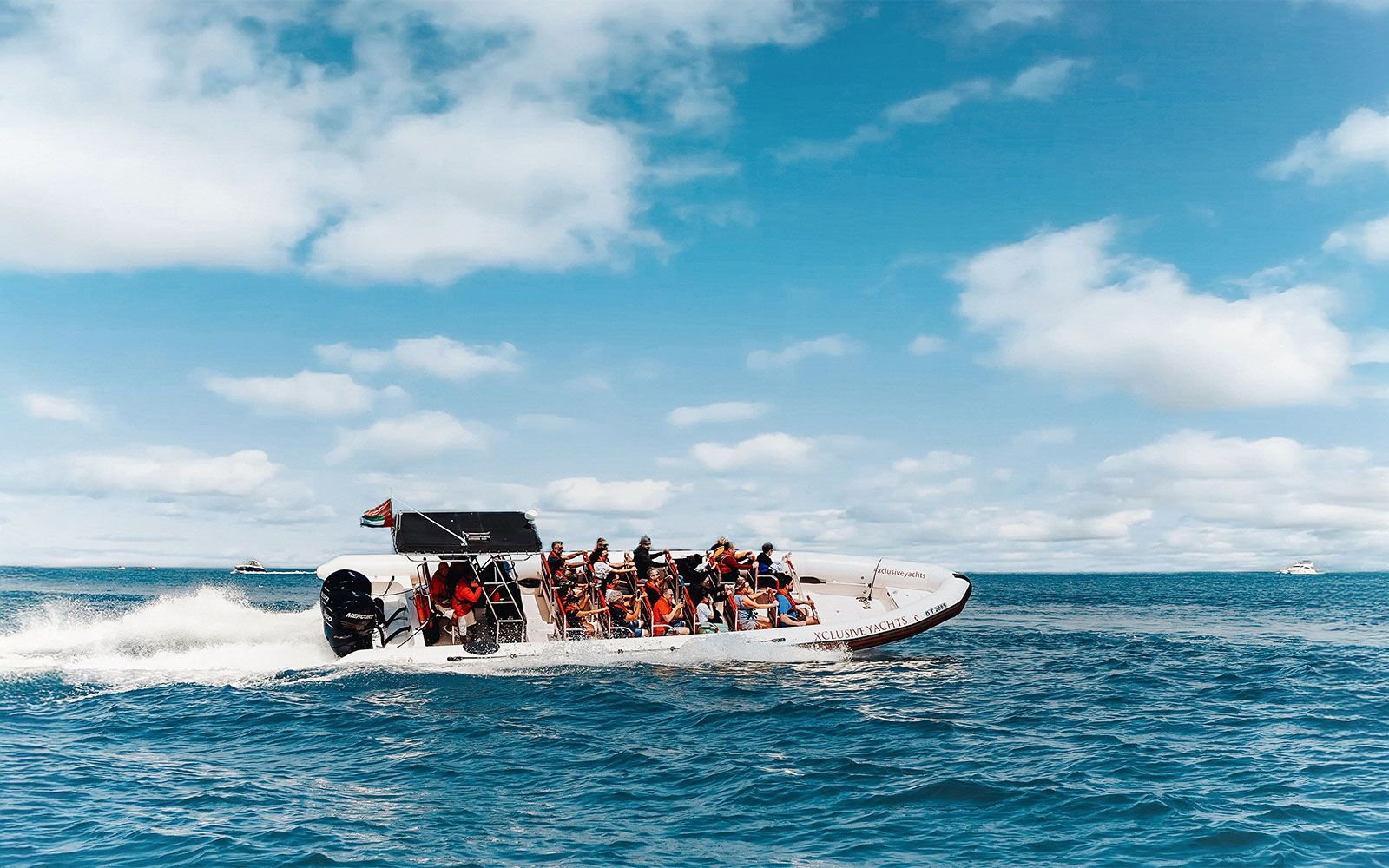 Speedboat with tourists on Dubai Marina tour, clear skies and ocean backdrop.