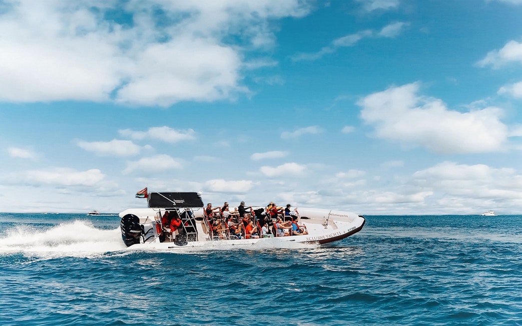 Speedboat with tourists on Dubai Marina tour, clear skies and ocean backdrop.