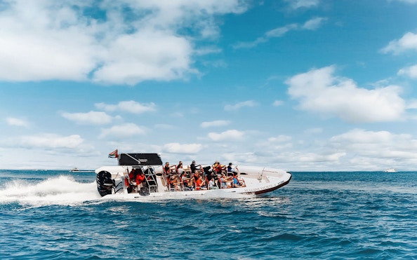 Speedboat with tourists on Dubai Marina tour, clear skies and ocean backdrop.