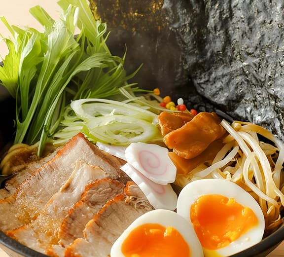 Bowl of ramen with soft-boiled eggs, pork slices, and vegetables at Tokyo cooking class.