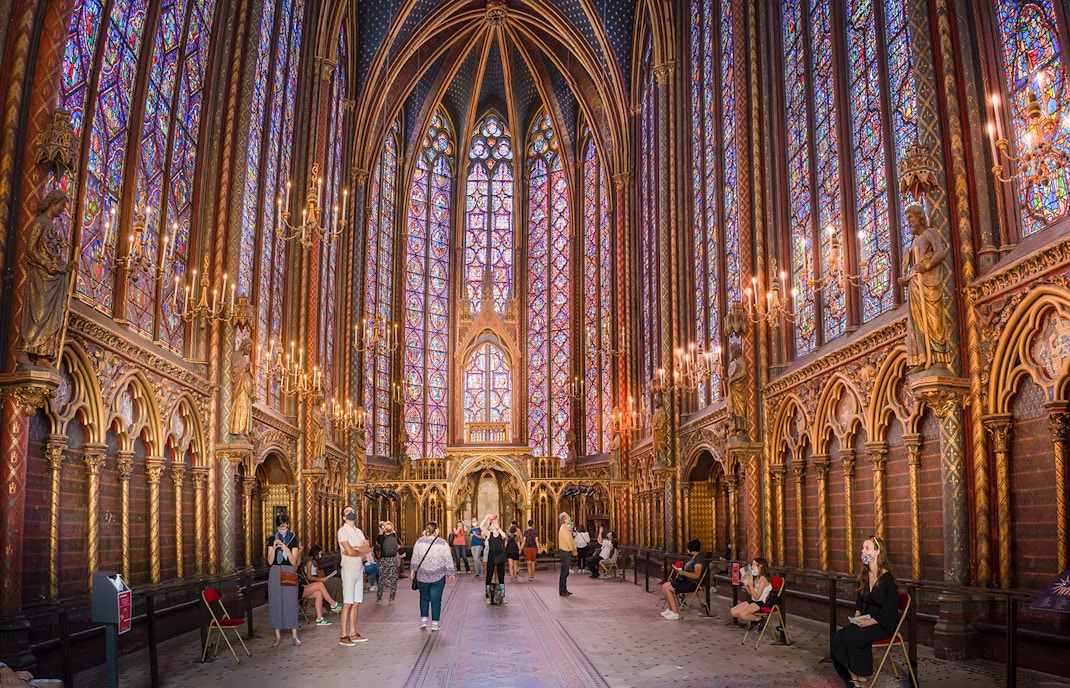 Visitors inside Sainte-Chapelle, Paris, admiring the stained glass windows.