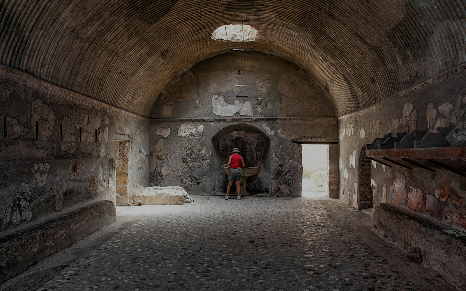 Tourist exploring ancient Herculaneum baths interior, Italy.