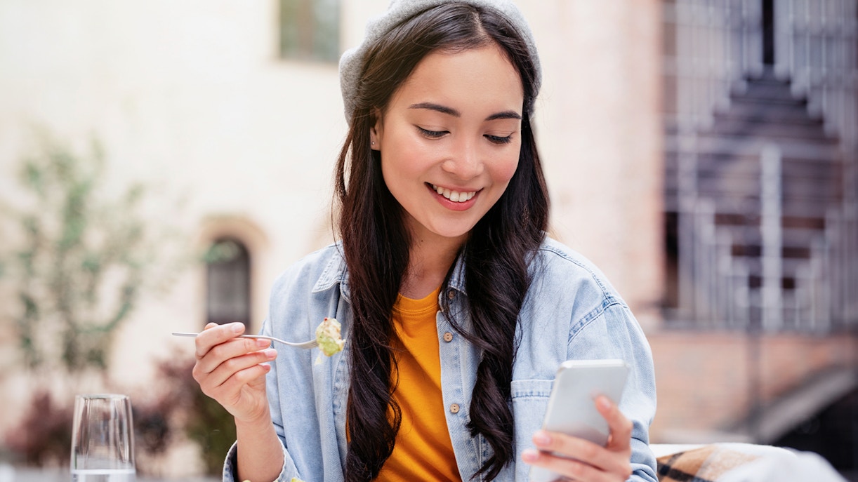 Woman looking into smartphone while eating at cafe