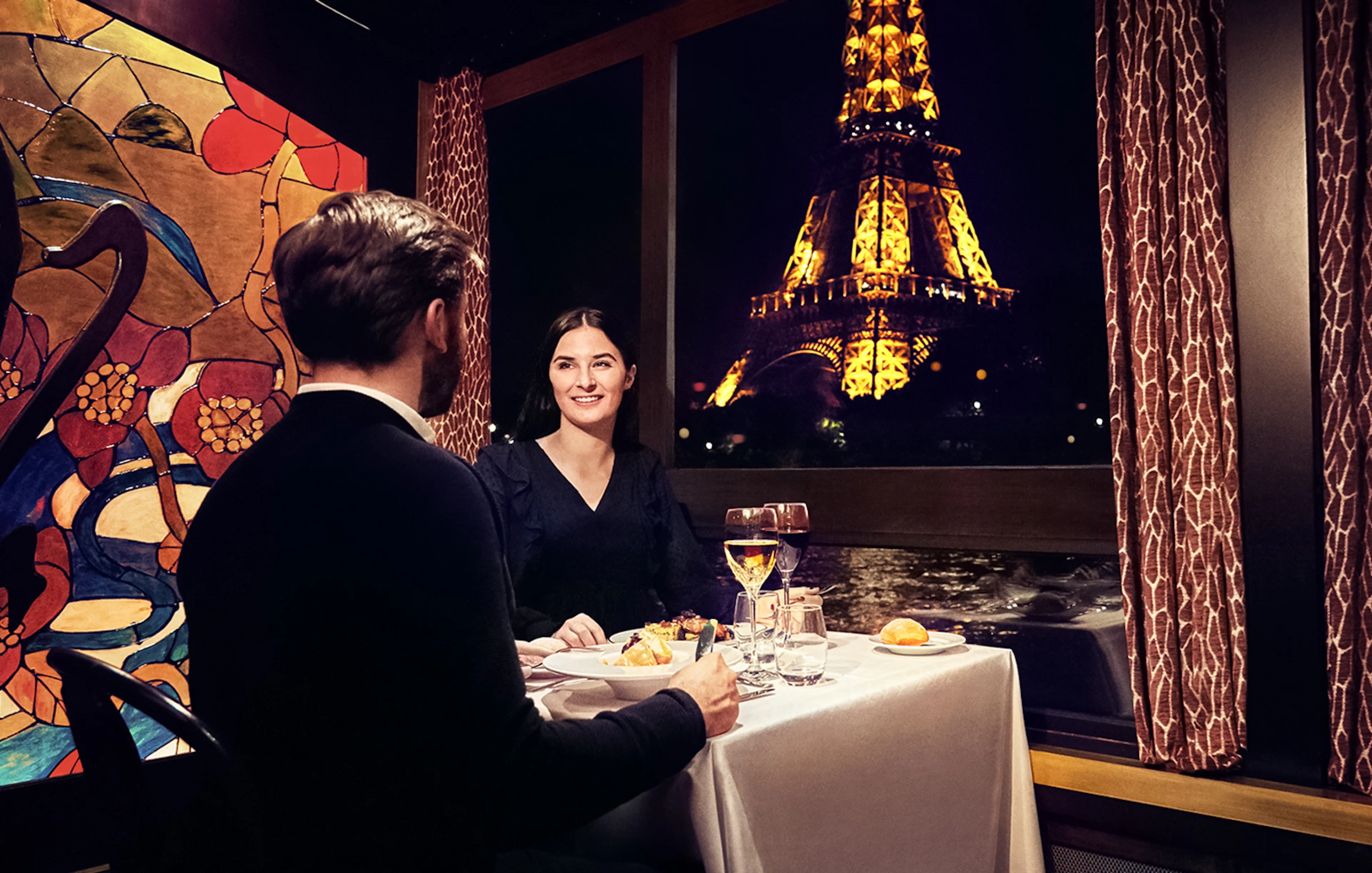 Couple dining on Maxim's Seine River Cruise with Eiffel Tower view.