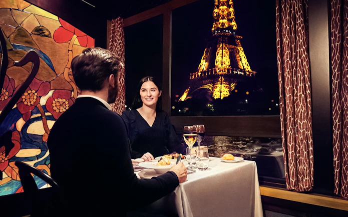 Couple dining on Maxim's Seine River Cruise with Eiffel Tower view.