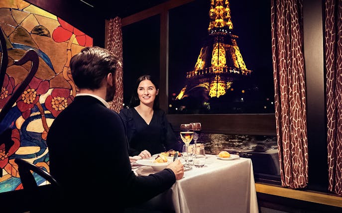 Couple dining on Maxim's Seine River Cruise with Eiffel Tower view.