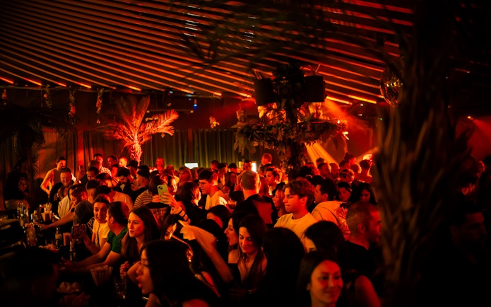 Crowded nightclub scene at Baloo Ibiza with people socializing under warm lighting.