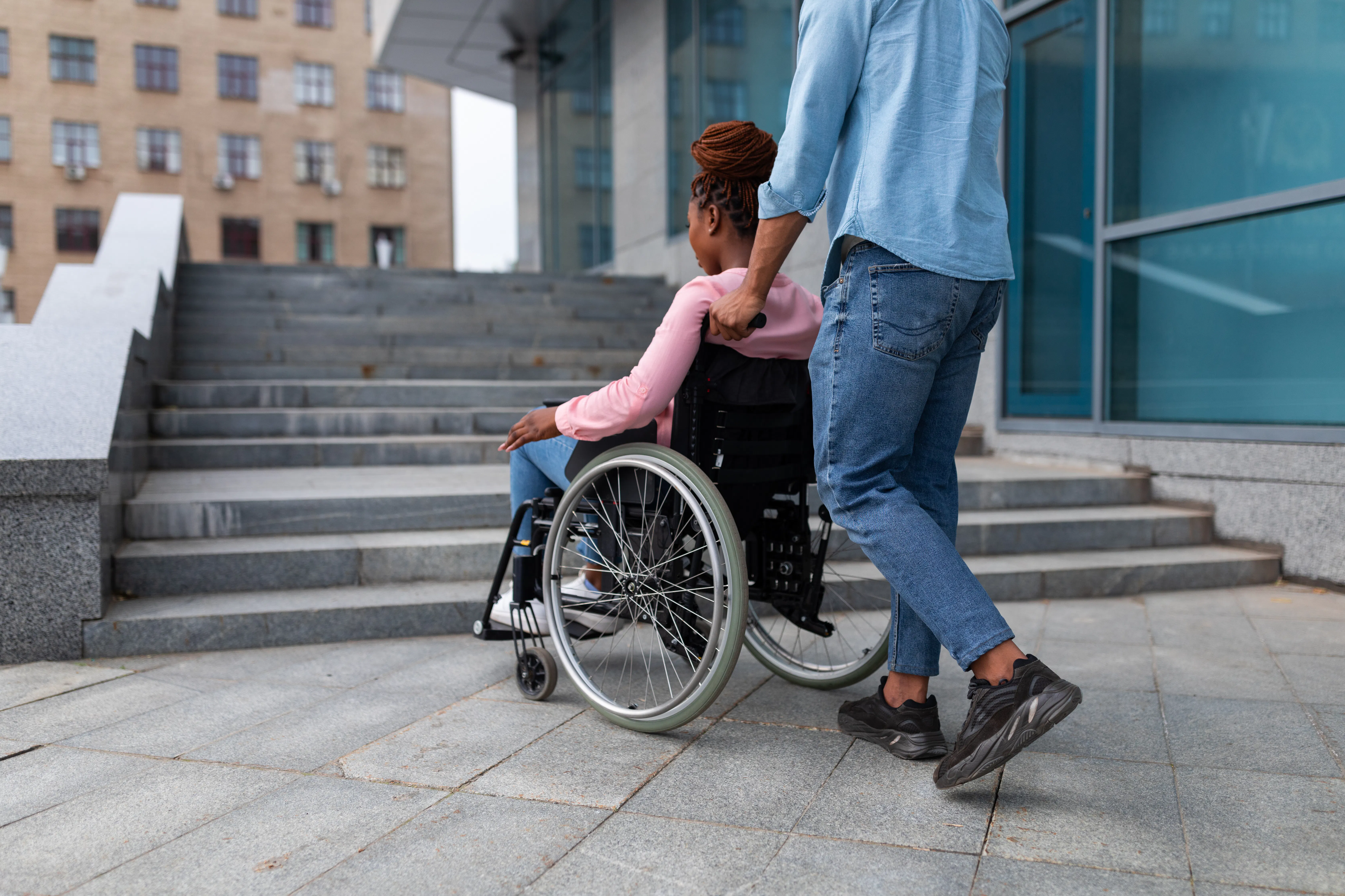 Person assisting wheelchair user near stairs, highlighting limited wheelchair access.