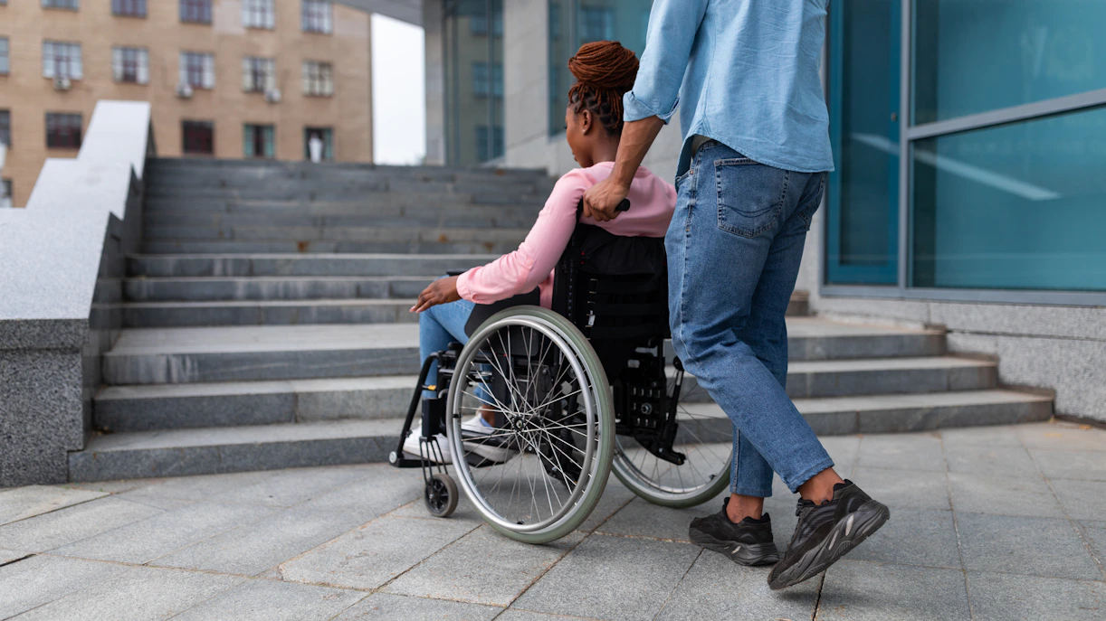 Person assisting wheelchair user near stairs, highlighting limited wheelchair access.