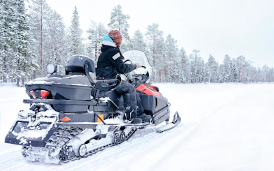 Woman riding snowmobile on a frozen lake in winter, Rovaniemi, Finland.
