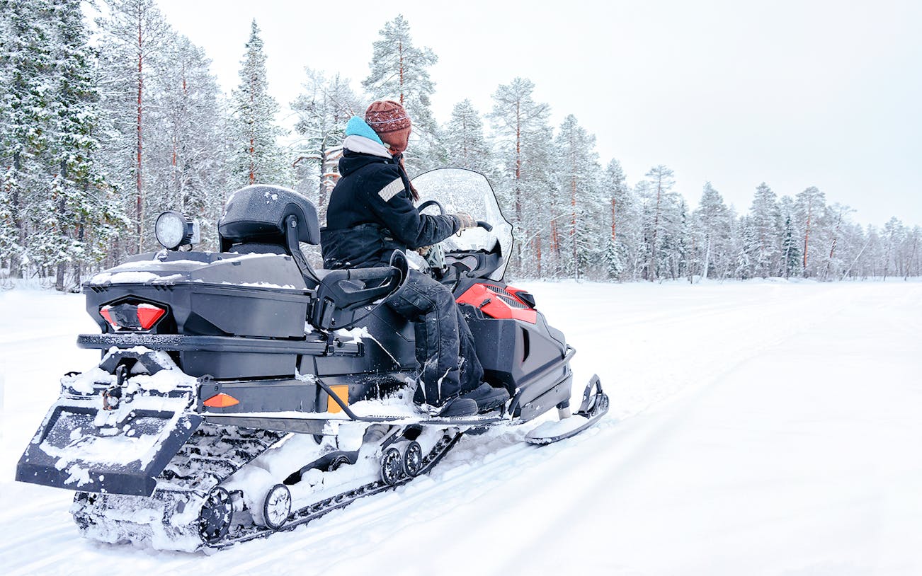 Woman riding snowmobile on a frozen lake in winter, Rovaniemi, Finland.