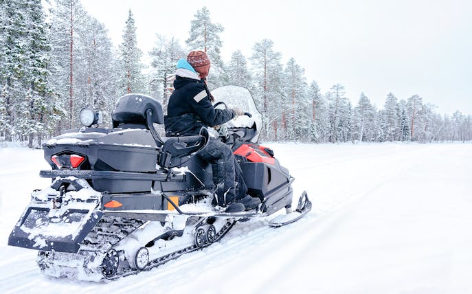 Woman riding snowmobile on a frozen lake in winter, Rovaniemi, Finland.
