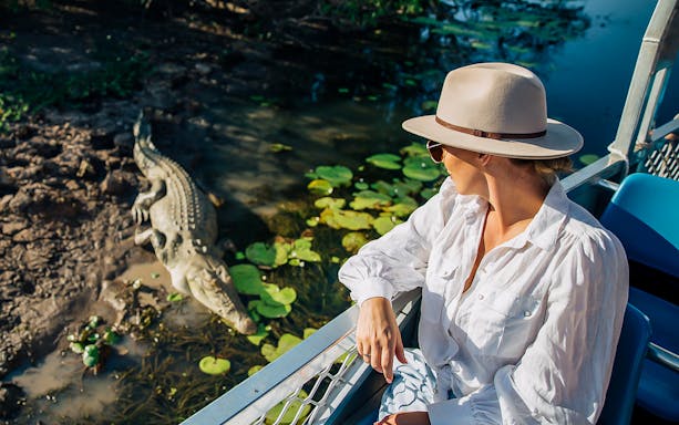 Tourist on Yellow Water Billabong cruise observing crocodile in Kakadu National Park.