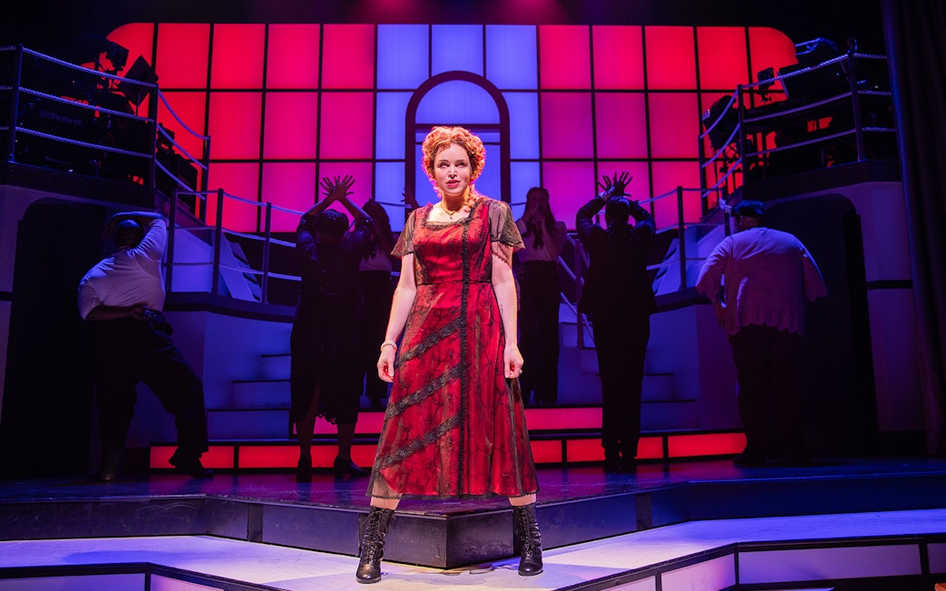 Performer in red dress on stage during Titanique musical.