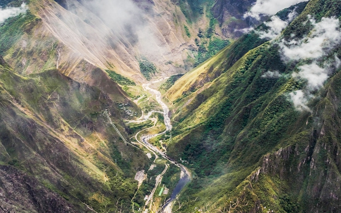 Panoramic view of Vilcanota Valley with winding river and lush green mountains.