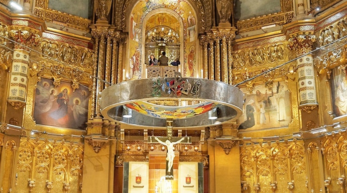 Monserrat Monastery altar with ornate gold detailing and religious artwork.