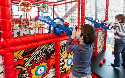 Children playing with ball cannons at Macau Kids City indoor playground.