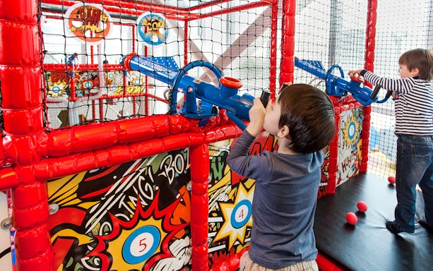 Children playing with ball cannons at Macau Kids City indoor playground.