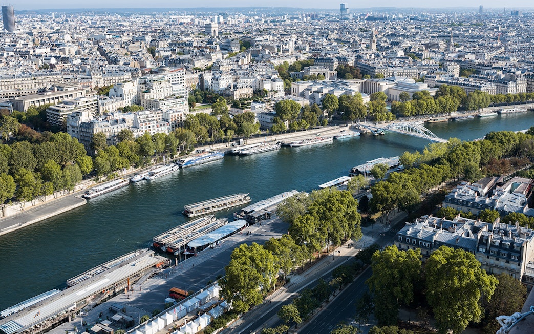 Aerial view of Seine River with cruise boats and Paris cityscape.