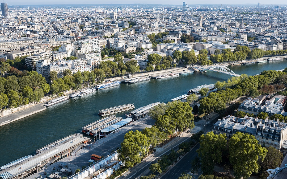 Aerial view of Seine River with cruise boats and Paris cityscape.