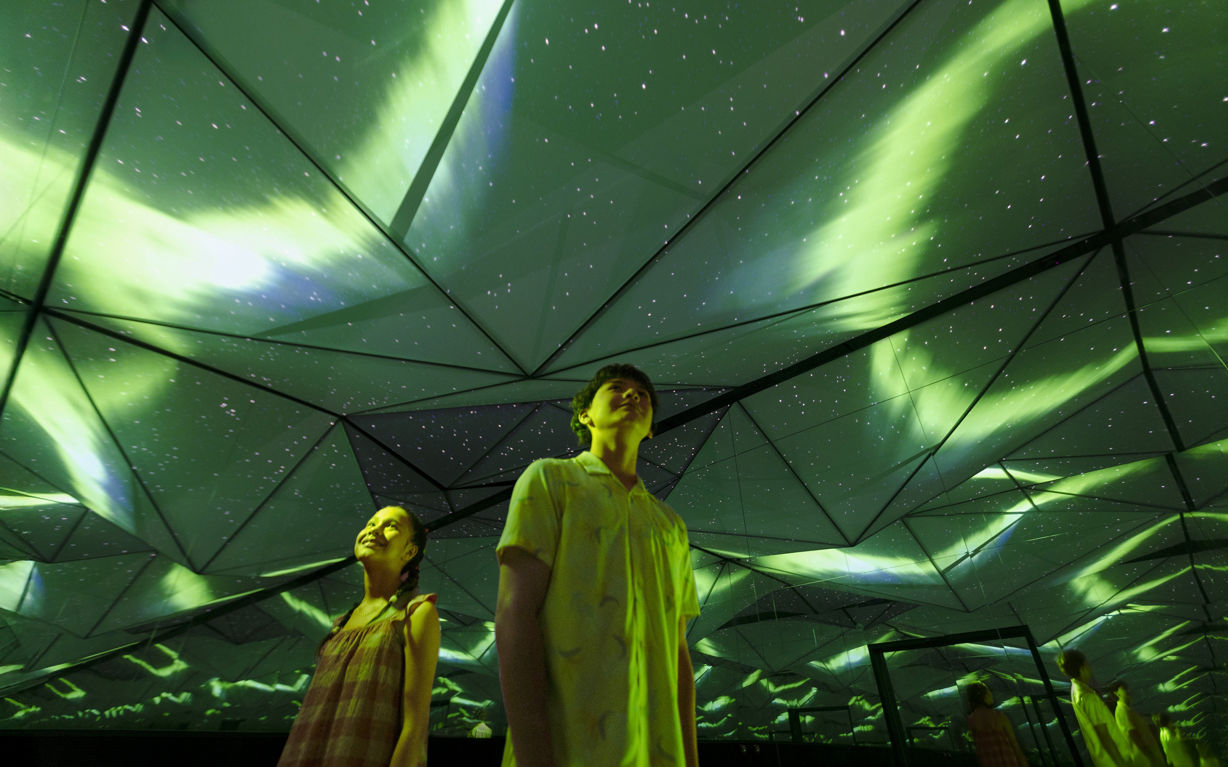 Visitors under simulated Northern Lights at Exploria's Arctic zone, Mandai Wildlife.