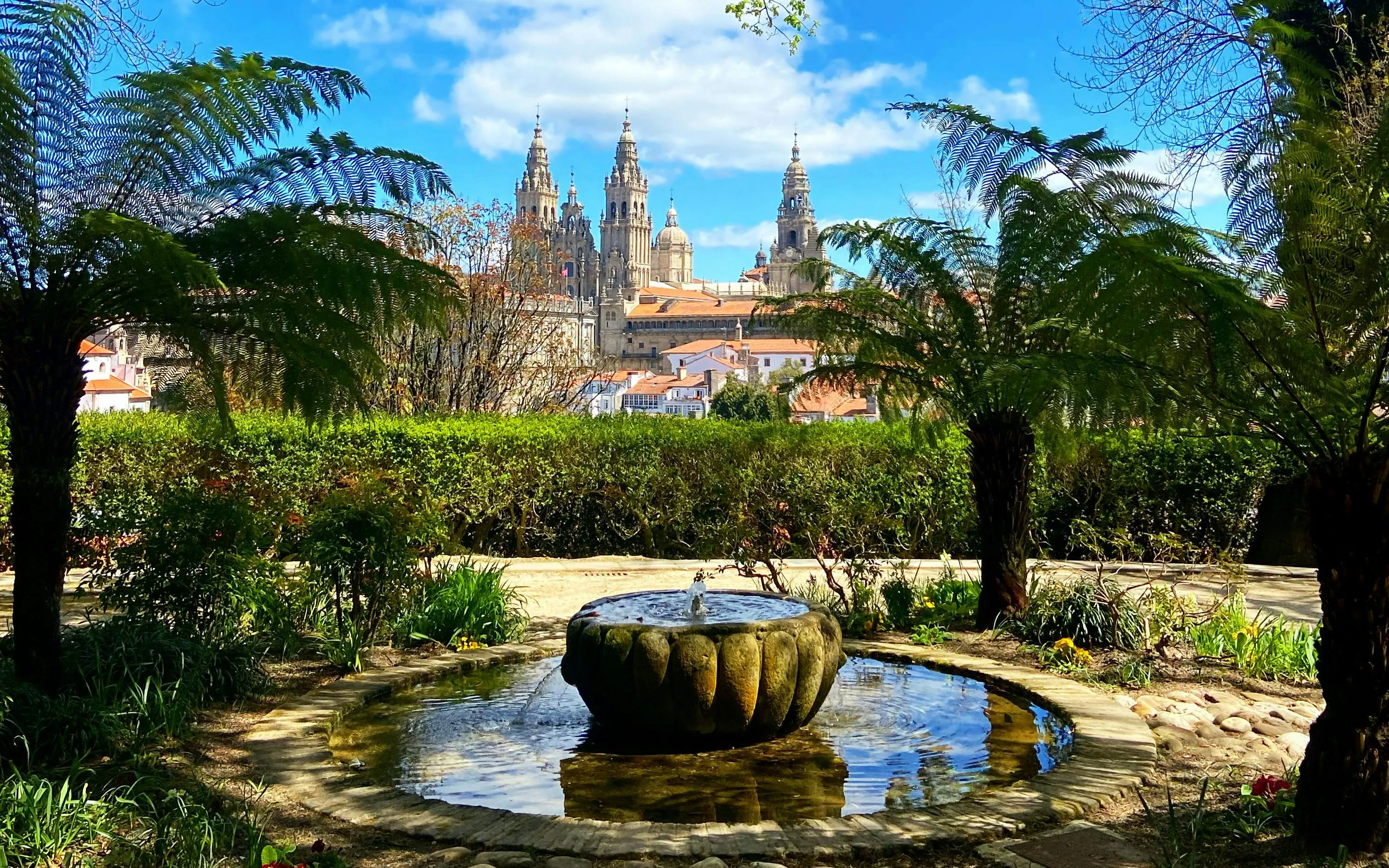 Santiago de Compostela Cathedral viewed from a garden with a stone fountain.
