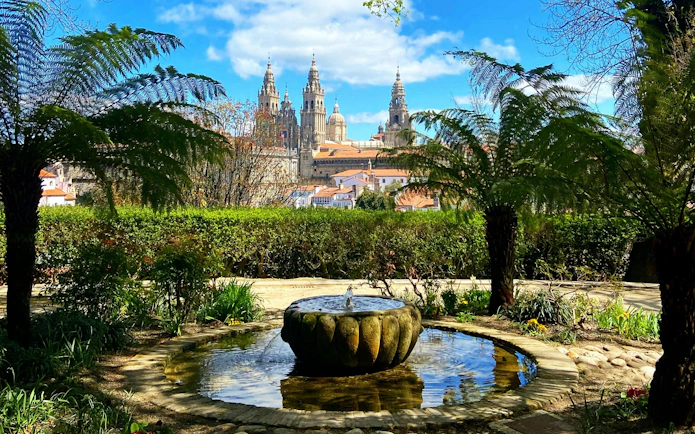 Santiago de Compostela Cathedral viewed from a garden with a stone fountain.