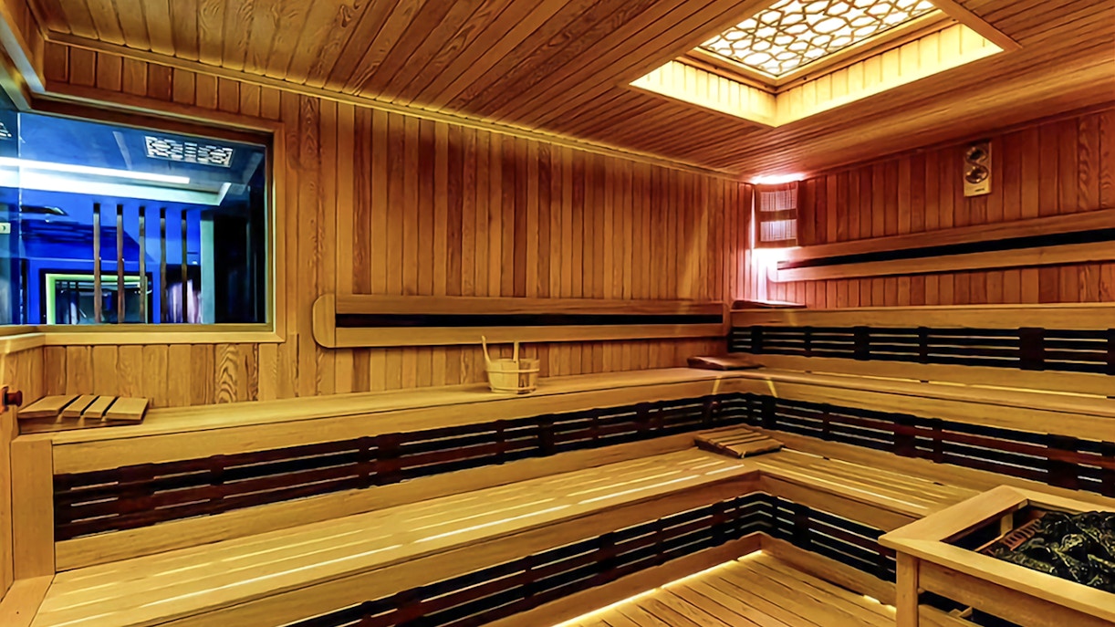 Interior of a wooden Turkish bath with benches and a central heating area.