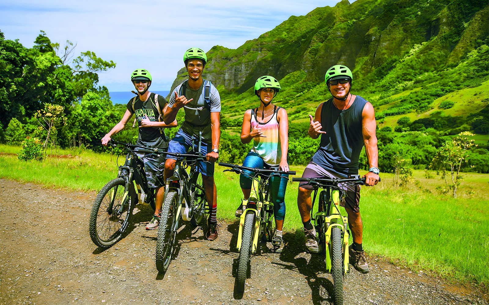 Group of cyclists on e-bikes at Kualoa Ranch, lush mountains in background.