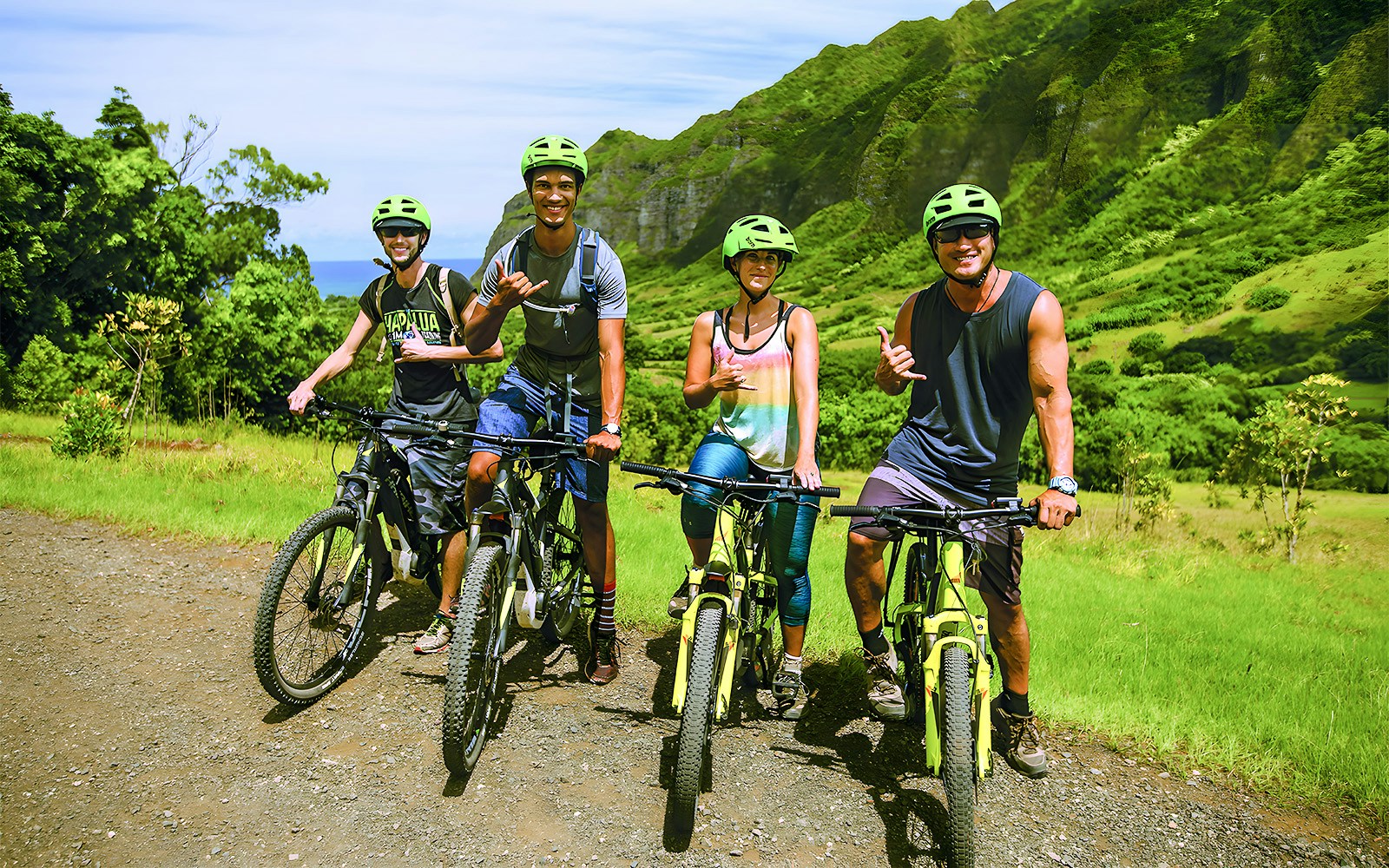 Group of cyclists on e-bikes at Kualoa Ranch, lush mountains in background.