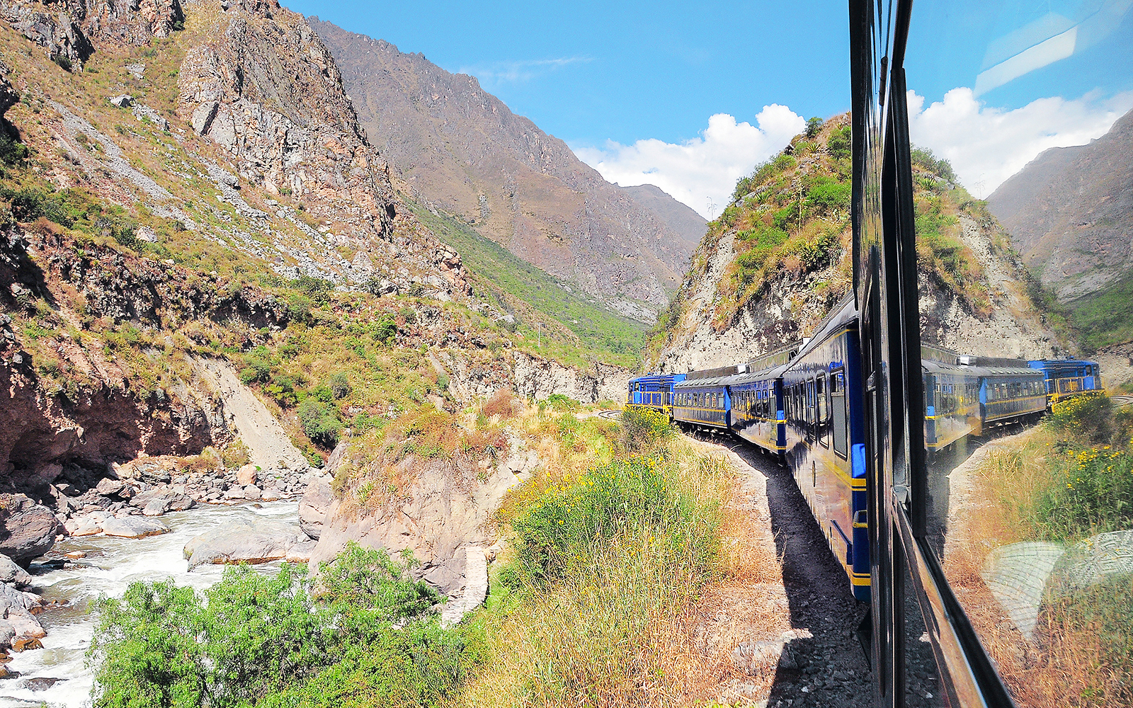 Train traveling through Andes mountains from Ollantaytambo to Machu Picchu pueblo.