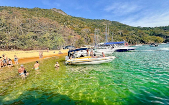 Boats anchored near a beach with people swimming in Arraial do Cabo, Brazil.