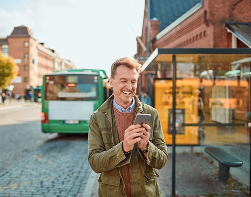 Person using navigation app on hop-on hop-off bus in city.