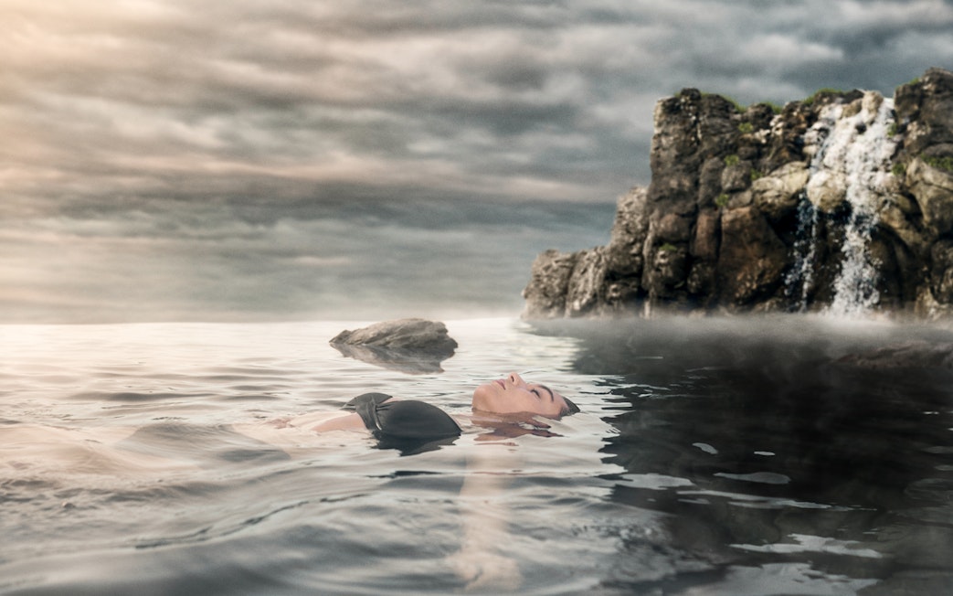 Person relaxing in Sky Lagoon with waterfall, Saman Pass.