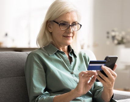 Woman purchasing tickets on smartphone with credit card.