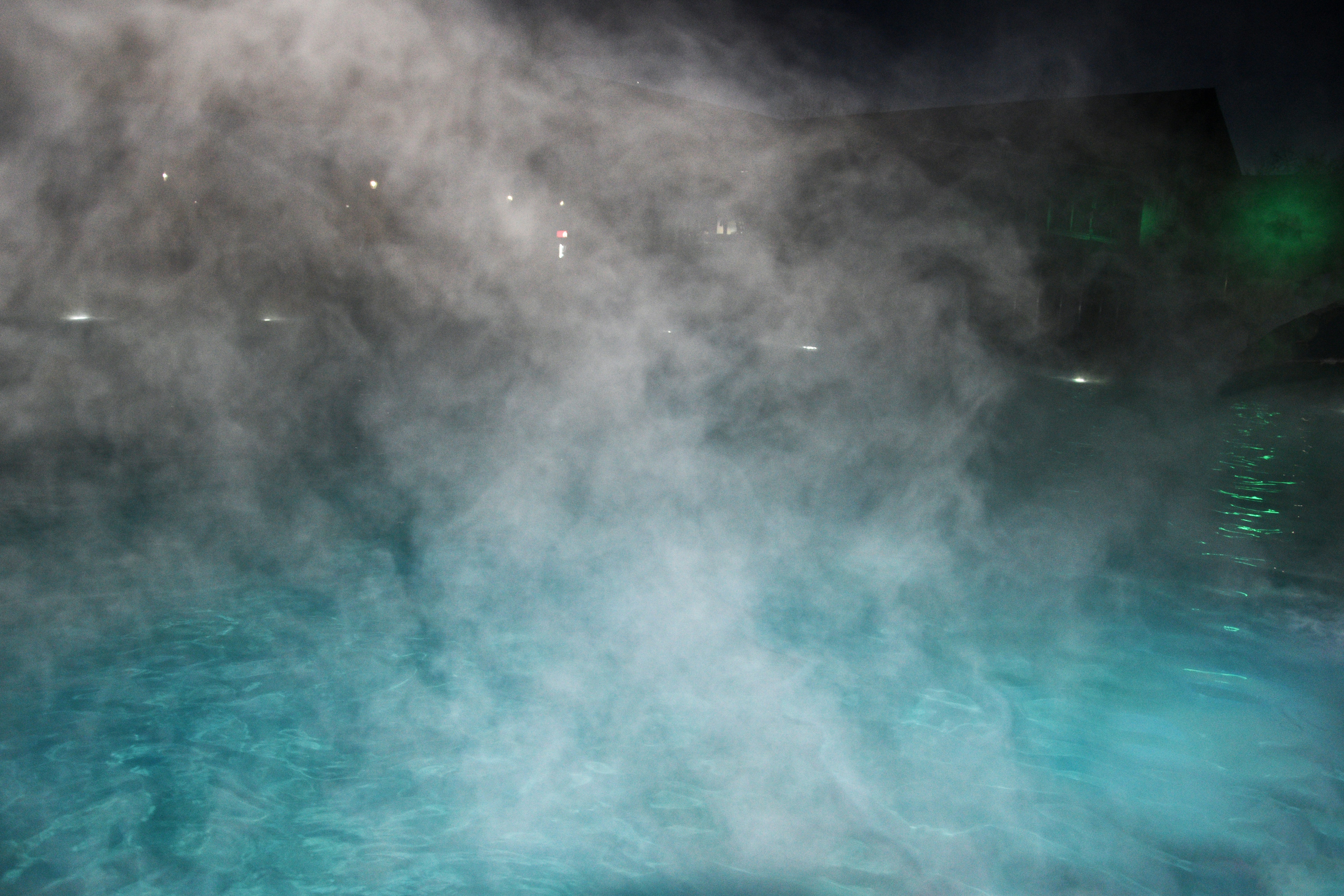 Geothermal pool with steam rising at night.