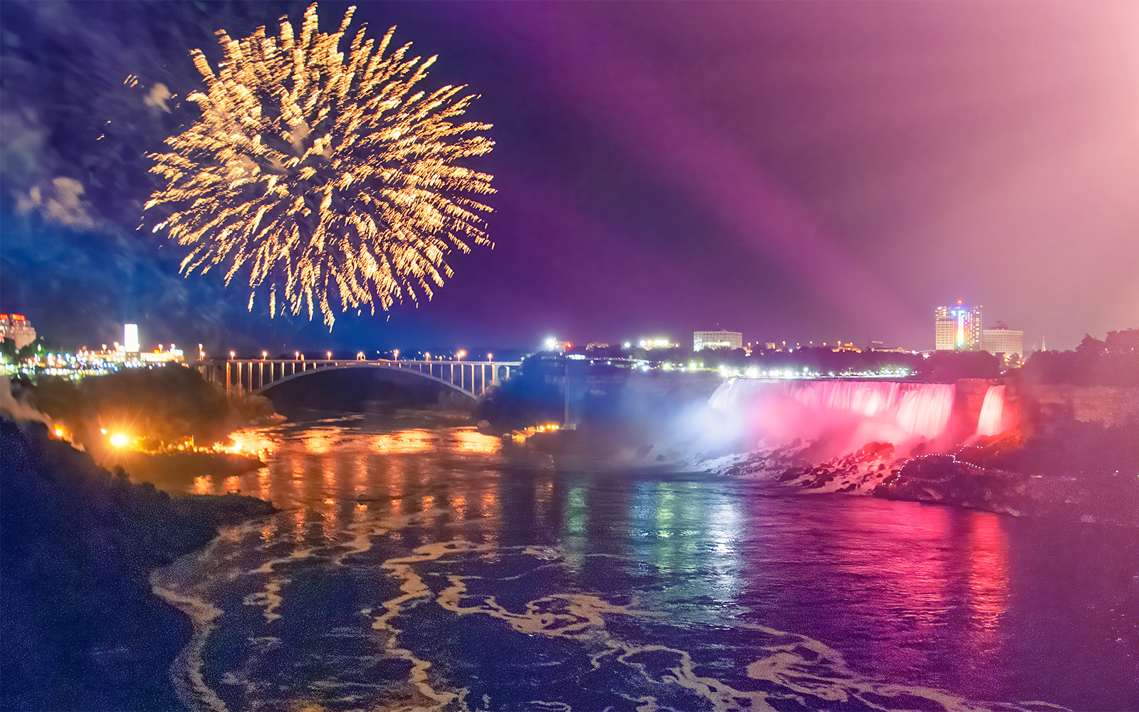 Niagara Falls illuminated in vibrant colors during the evening light show.