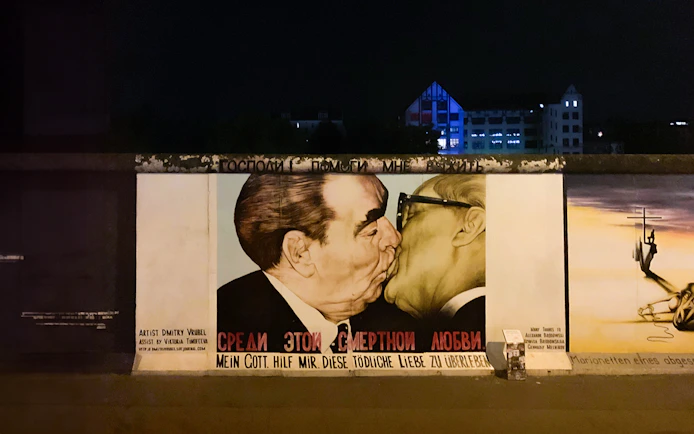 Berlin Wall mural at night featuring a famous political artwork.