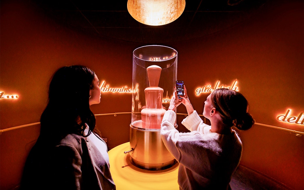 Tourists photographing chocolate fountain at Chocoversum, Hamburg.