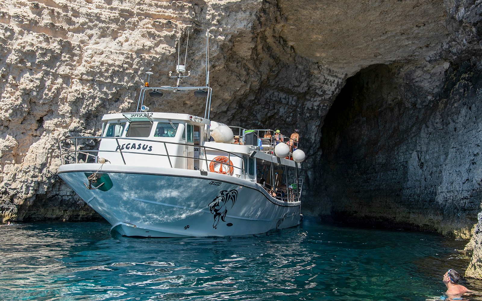 People enjoying a cruise at the Blue Lagoon, Malta, with clear blue waters and scenic views.
