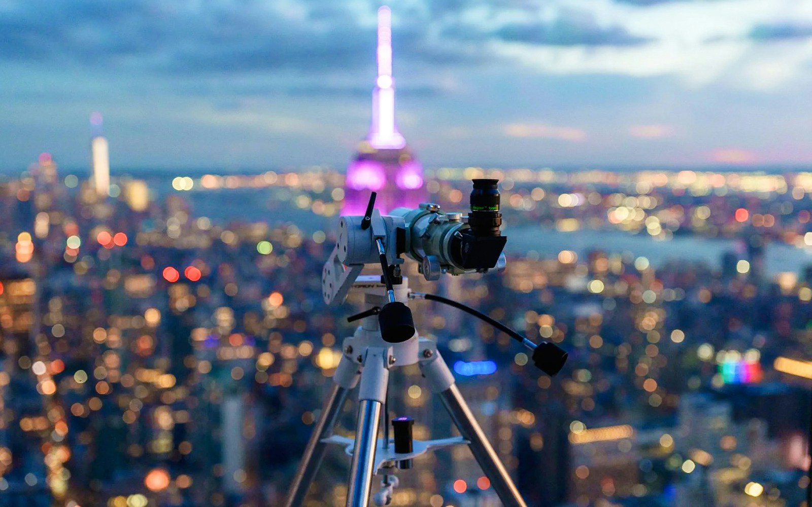 Visitors stargazing through telescopes at Summit One Vanderbilt, New York City skyline in the background.