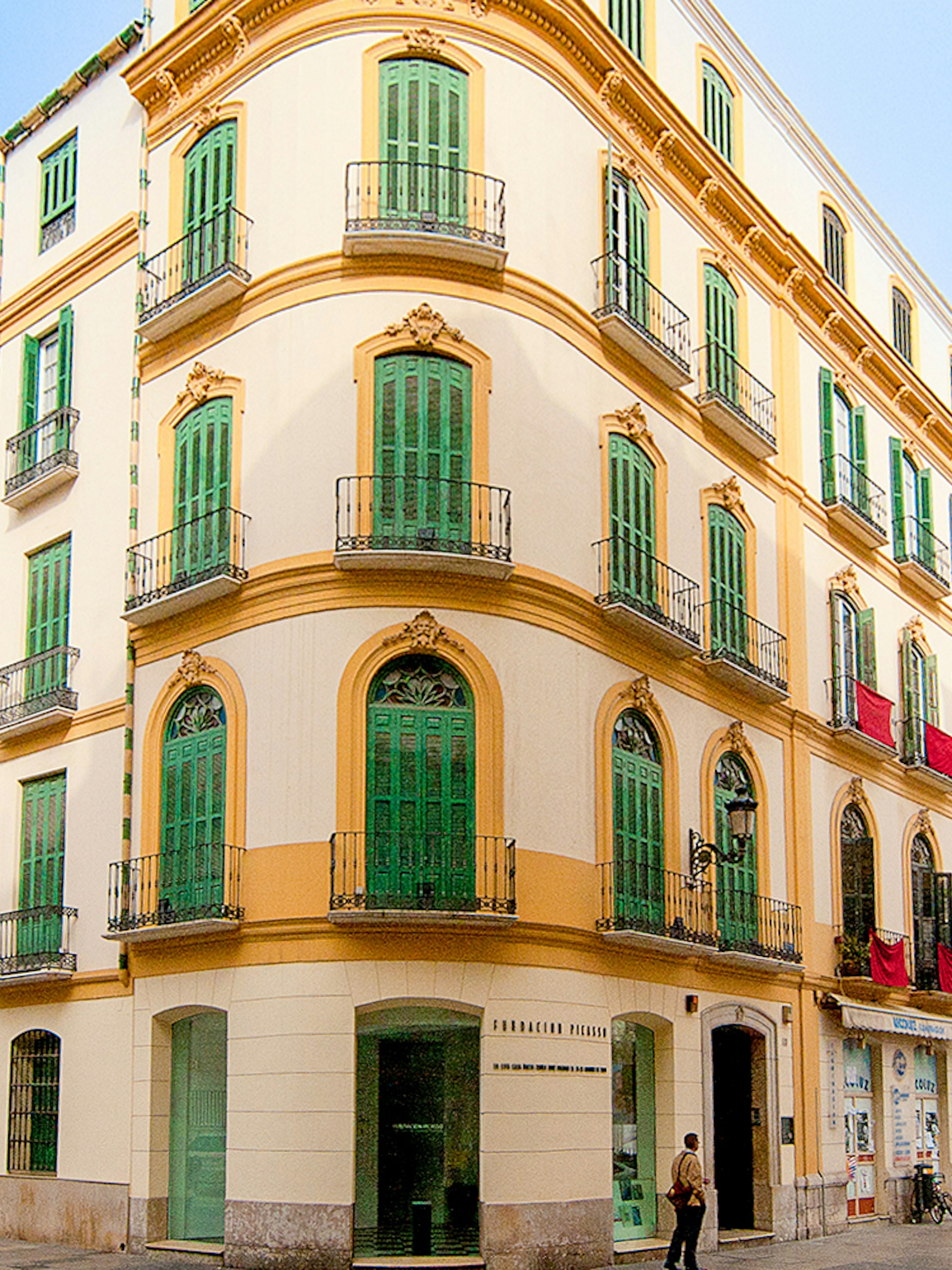 Facade of Picasso's Birthplace Museum in Málaga with green shutters and balconies.